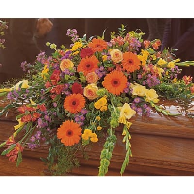 Colorful floral casket spray with orange gerberas and yellow roses