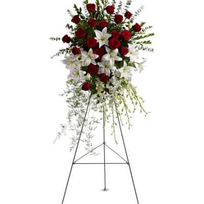 Standing floral spray of red roses and white lilies on an easel
