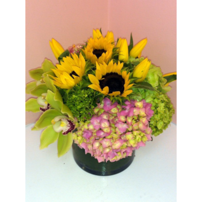 Bouquet of sunflowers, yellow lilies, and pink hydrangeas in a dark vase