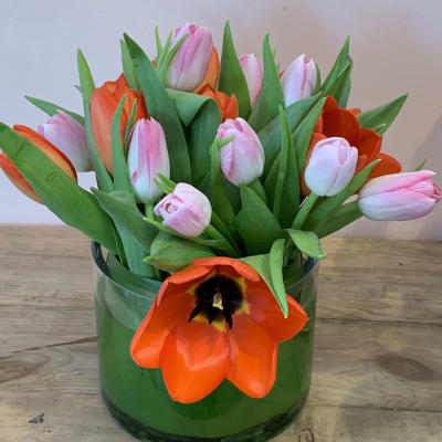 Pink and orange tulips arranged in a green glass vase