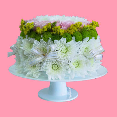 White and green floral arrangement on a pedestal stand with ribbon bows