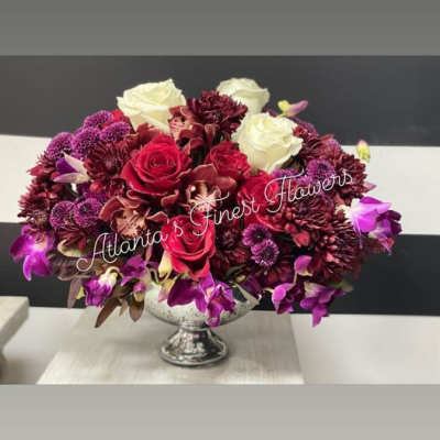 Red, white, and purple floral arrangement in a silver pedestal vase