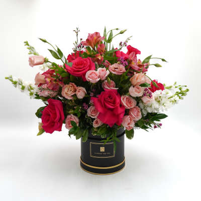 Pink and white mixed flower arrangement in a black hatbox