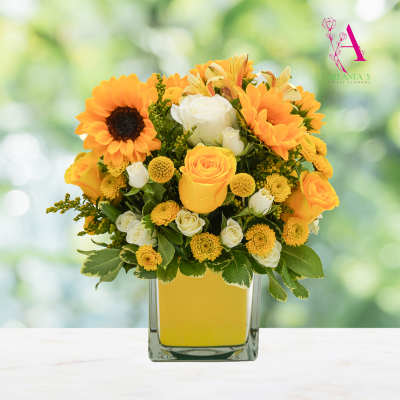 Yellow and white flowers arranged in a square glass vase