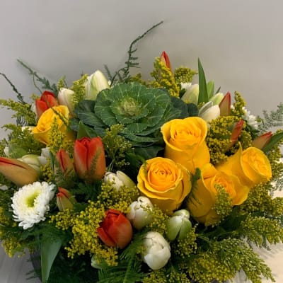 Yellow roses and red tulips arranged in a black bowl vase