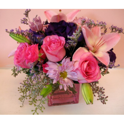 Pink roses and lilies arranged in a square glass vase