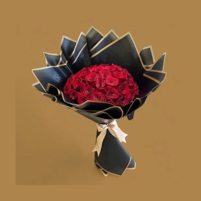 Bouquet of red roses wrapped in black paper with a ribbon