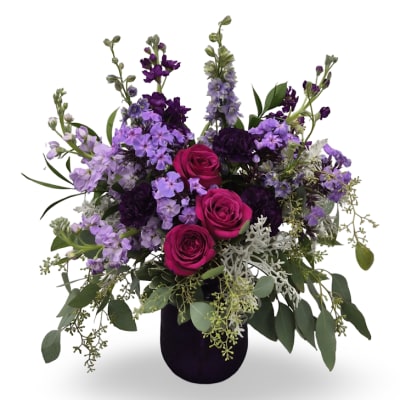 Purple and pink rose arrangement in a dark vase