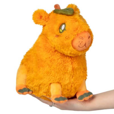 Orange plush cow with a pumpkin on its head, held in a hand