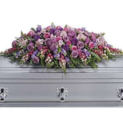 Long pink and purple casket spray arrangement on a silver casket