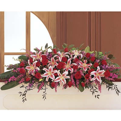 Long floral arrangement with red roses and pink lilies in a white container