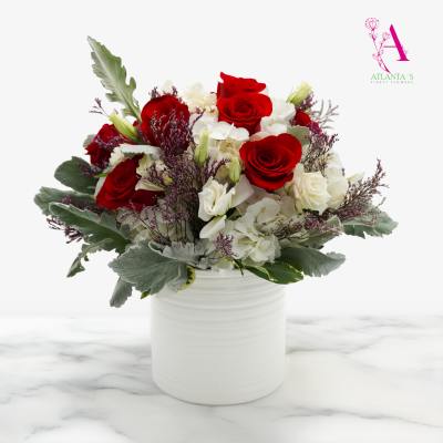 Red roses and white flowers arranged in a white vase
