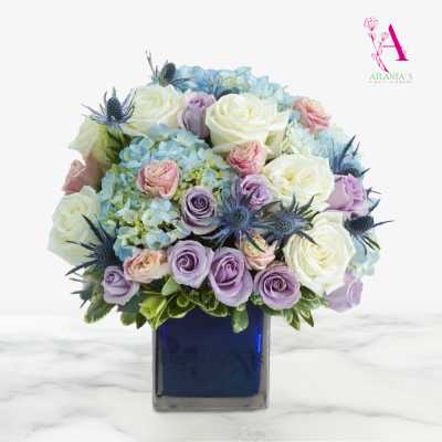 Bouquet of pastel roses and hydrangeas in a blue glass vase