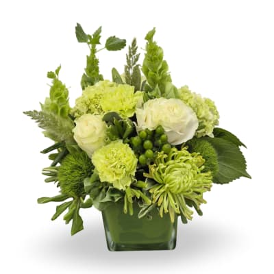 Green and white floral arrangement in a square glass vase