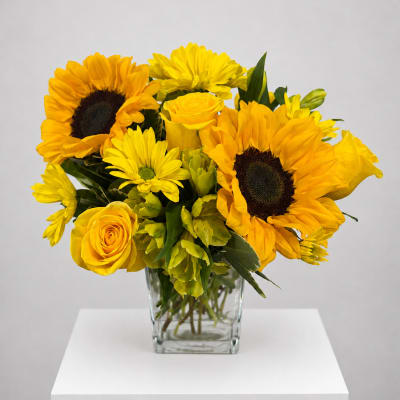 Yellow sunflower and rose bouquet in a clear glass vase