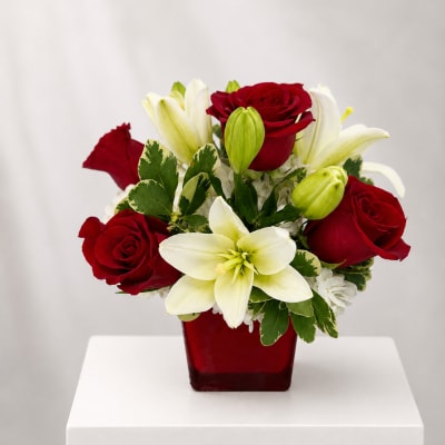 Red roses and white lilies arranged in a red square vase