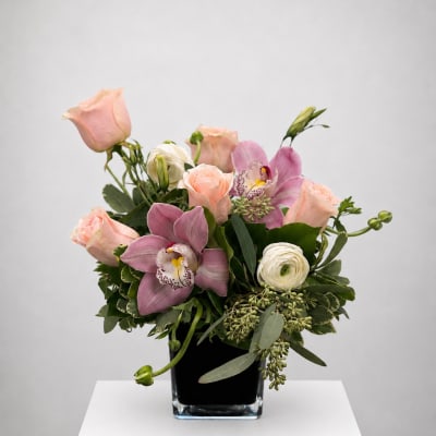 Pink roses and orchids arranged in a black vase