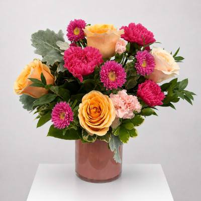 Bouquet of peach roses and pink daisies in a glass vase