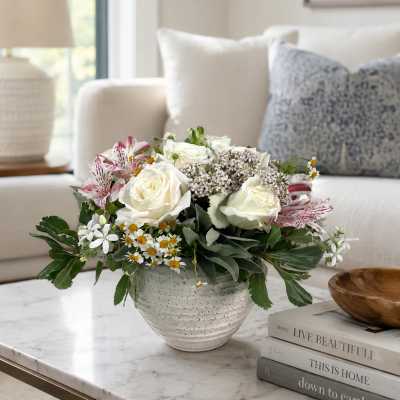 White roses and pink alstroemeria in a speckled ceramic vase