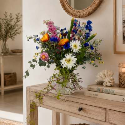 Mixed bouquet of colorful flowers in a clear glass vase on a wooden table