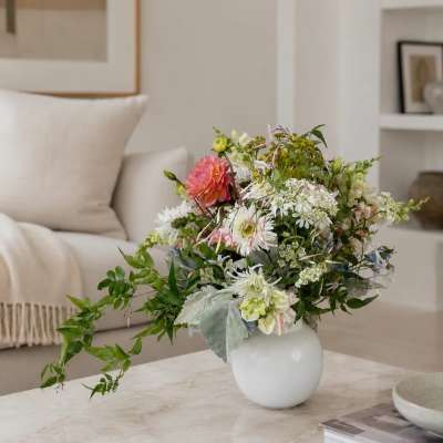 Mixed bouquet in a white round vase with pink, white, and green flowers