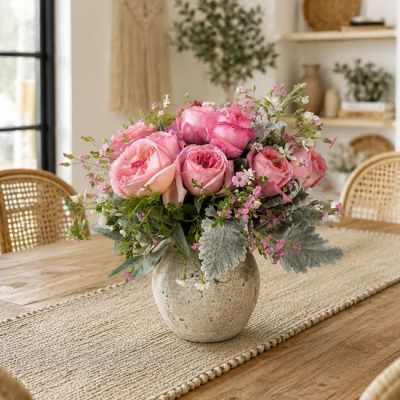 Pink rose bouquet in a round ceramic vase on a dining table