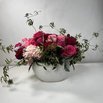 Mixed pink and red roses arranged in a white bowl vase