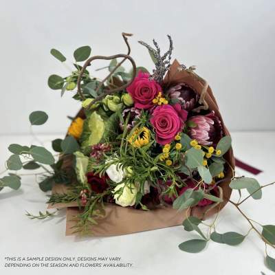 Bouquet of pink roses and mixed blooms wrapped in brown paper