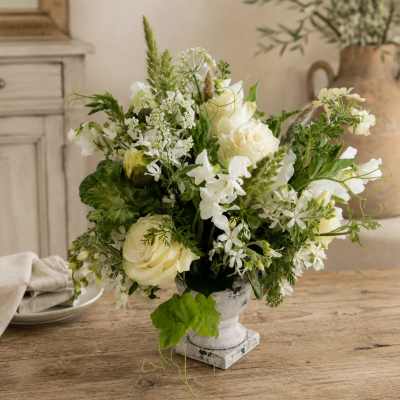 White rose and mixed white flower arrangement in a small pedestal vase