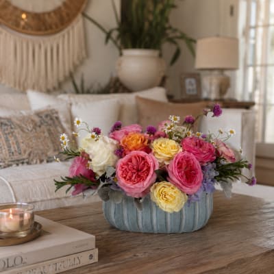 Pink and yellow roses in a blue ceramic bowl with small daisy accents