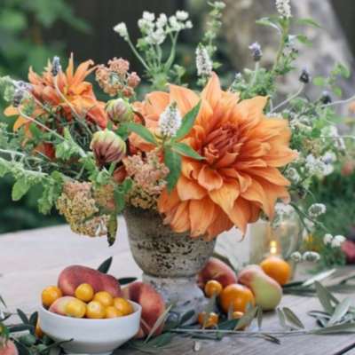 Orange dahlia arrangement in a rustic vase with airy wildflowers