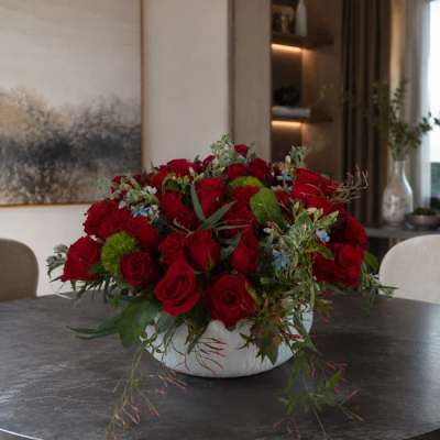 Red rose arrangement in a white bowl vase