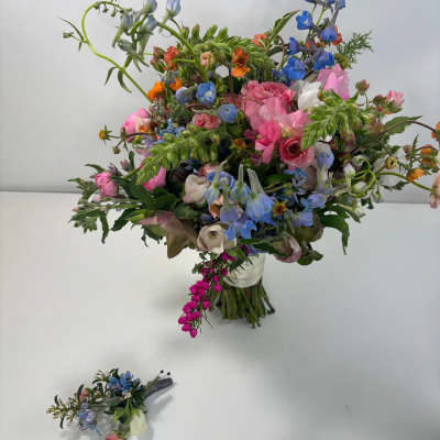 Loose bouquet of pink, blue, and white flowers in a clear vase