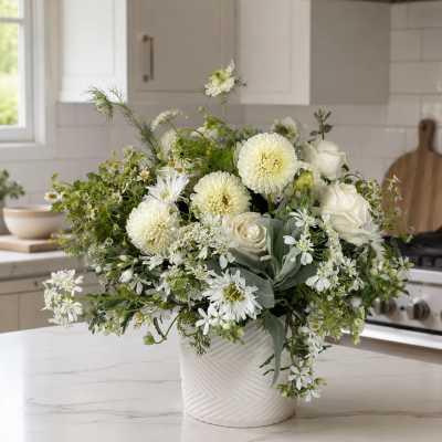 White floral arrangement in a textured white vase on a kitchen counter