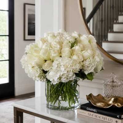 White roses and hydrangeas arranged in a clear glass vase