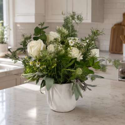 White roses and small white daisies in a white vase
