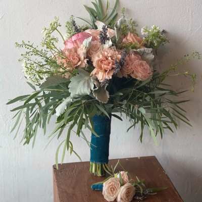 Blush rose bouquet with greenery and a matching boutonniere on a table