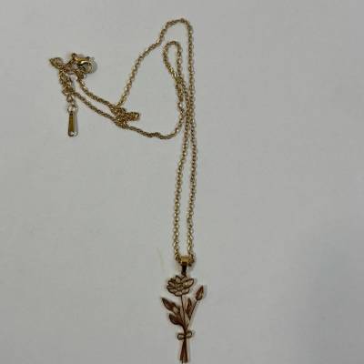Gold-tone necklace with a floral pendant on a plain background