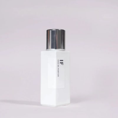 White perfume bottle with a silver cap on a pale background