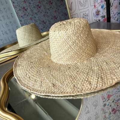 Two woven straw hats on a mirrored surface