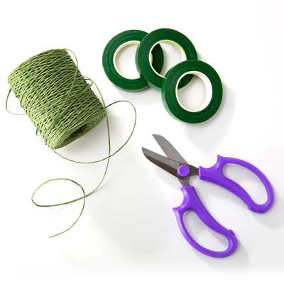 Green floral tape, twine, and purple-handled scissors on a white background