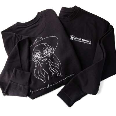 Two black sweatshirts with white floral line art and text