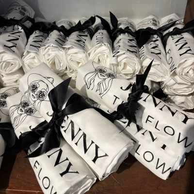 Rolled white fabric bundles tied with black ribbons and printed with floral graphics