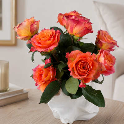 Orange and pink roses in a white ceramic vase
