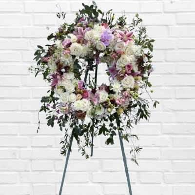 Large floral wreath on an easel with white, pink, and lavender flowers