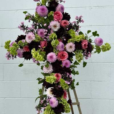 Cross-shaped floral arrangement with pink, purple, white, and green blooms