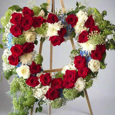 Heart-shaped floral wreath with red and white roses on a wooden easel