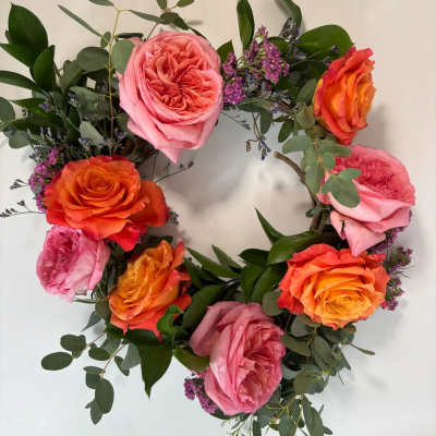Circular wreath of pink and orange roses with purple filler flowers