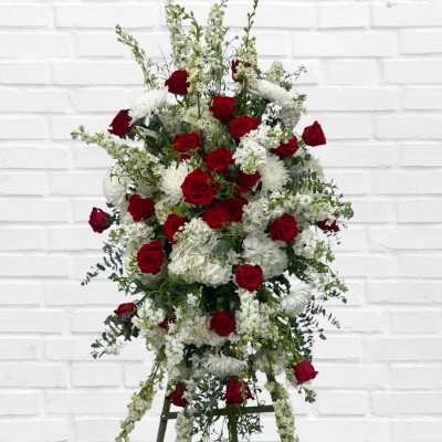Standing floral spray of red roses and white flowers on an easel