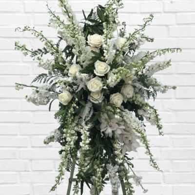 Tall white floral standing arrangement with roses and cascading blooms